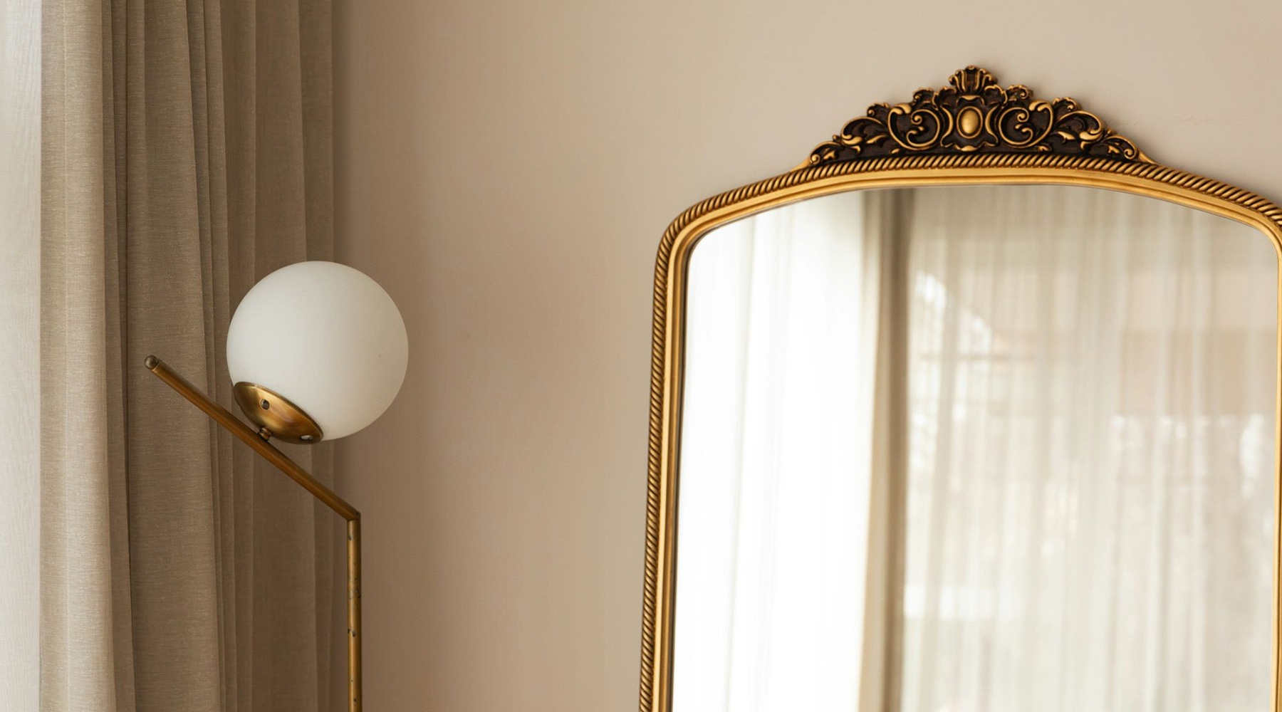 A large mirror next to a lamp and window.